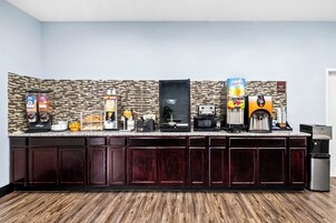 Una cocina moderna con protector de piedra, armarios de madera oscura y diversos electrodomésticos, incluyendo una cafetera, microondas y tostadora.