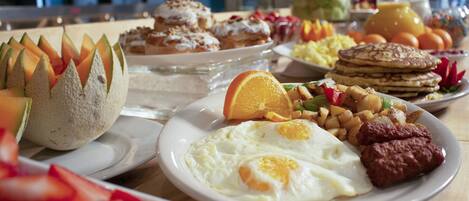 A breakfast buffet with various dishes including eggs, sausages, and pastries.