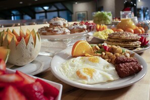 A breakfast buffet with various dishes including eggs, sausages, and pastries. - MCM Grande Hotel FunDome Odessa (Odessa)