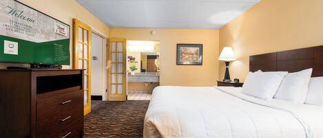 Habitación de hotel con cama, cómoda, espejo y cartel de bienvenida.