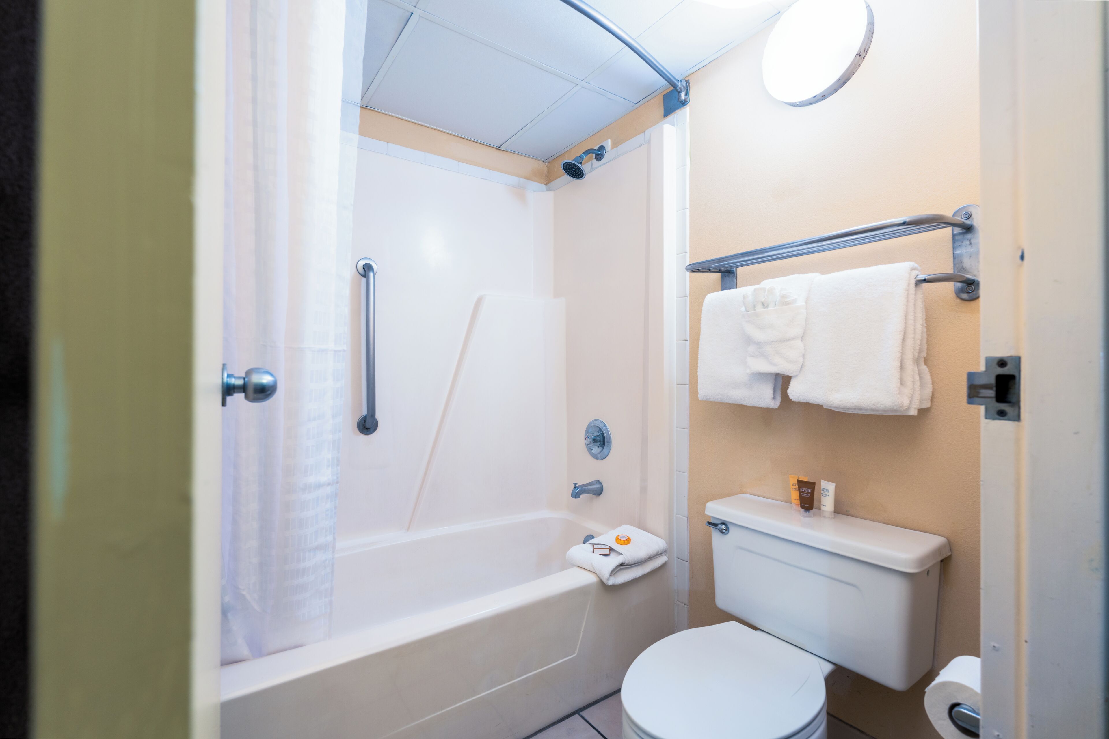 A bathroom with a bathtub, toilet, and a towel rack.