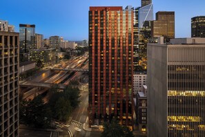 A high-rise building with a modern design, surrounded by other tall buildings and a busy road with moving vehicles. - Crowne Plaza Seattle - Downtown by IHG (Seattle)