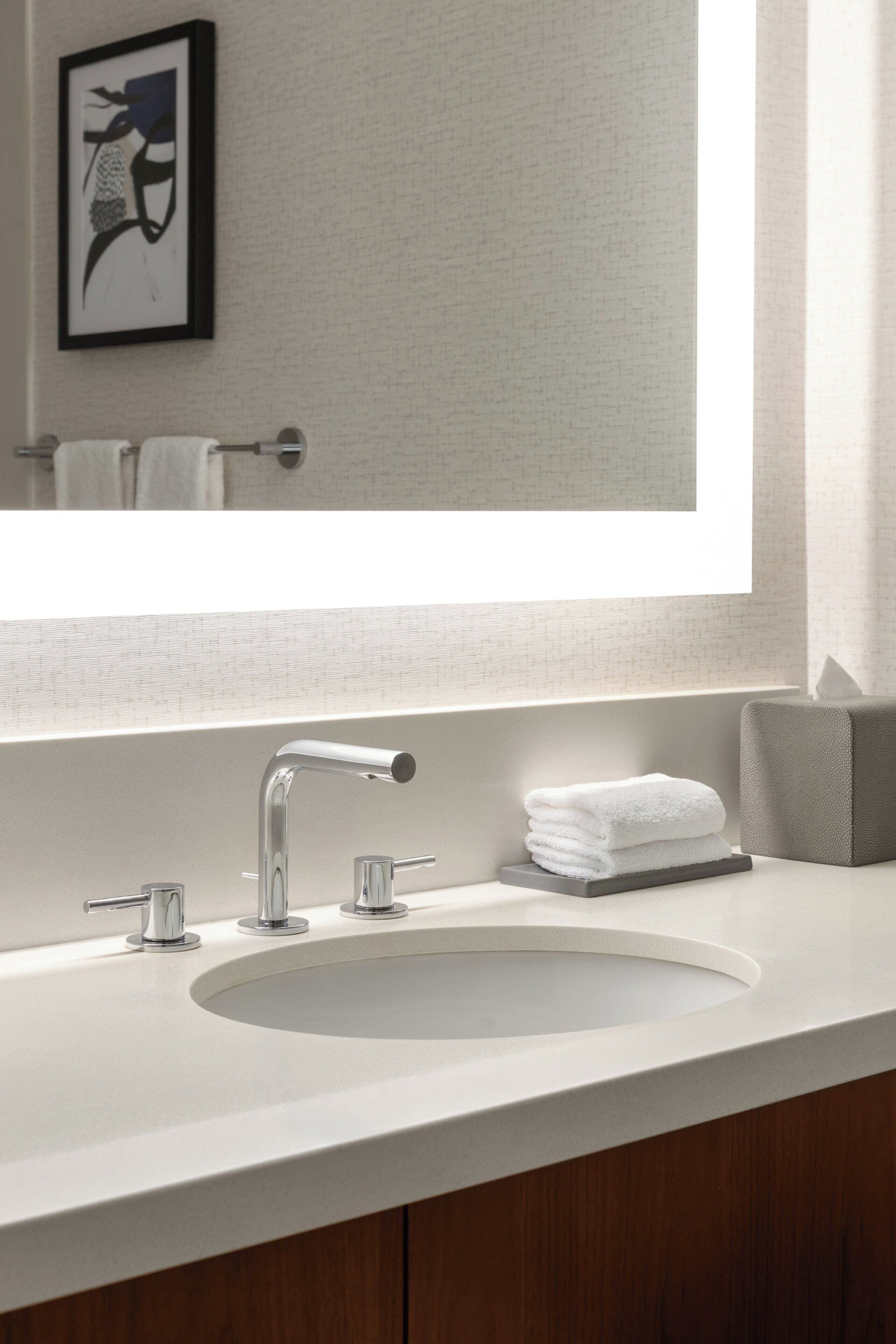 Un baño moderno con un espejo grande, un lavabo blanco y un perchero para toallas.