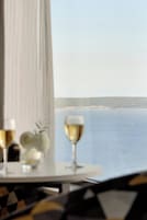 Et bord med et glas vin og en frugtanretning, med udsigt over vand.