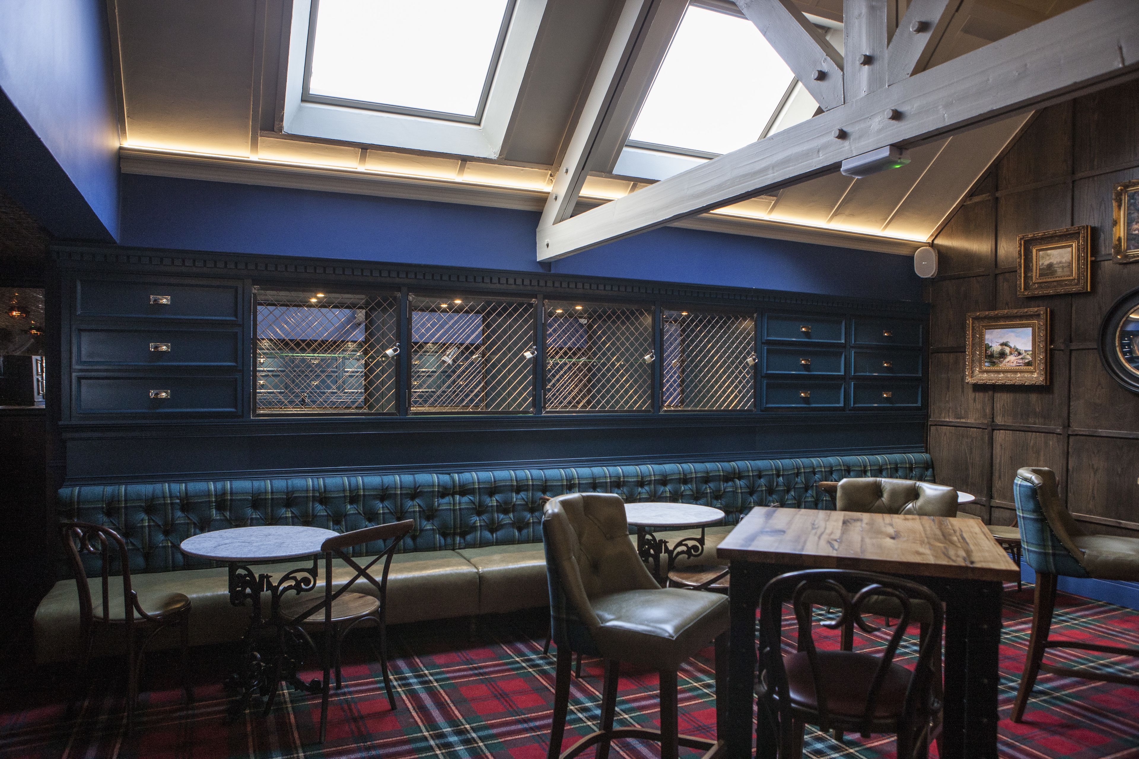 A cozy interior with a blue wall, a wooden bench, and a plaid carpet.