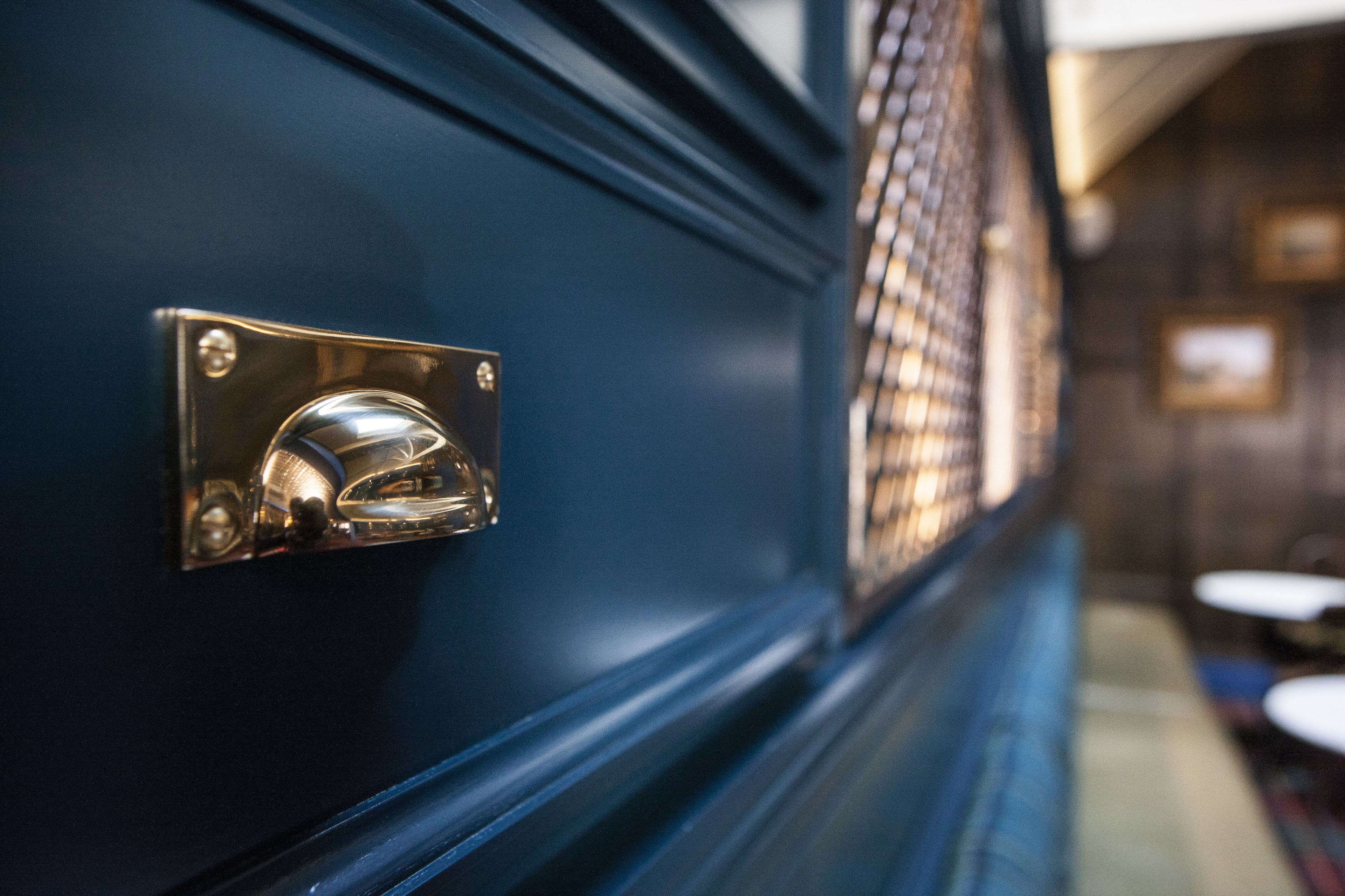 A close-up of a metallic handle on a dark blue door, with a blurred background suggesting a public space.