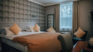 A hotel room with a large bed, a bedside table, a chair, and a window with curtains.