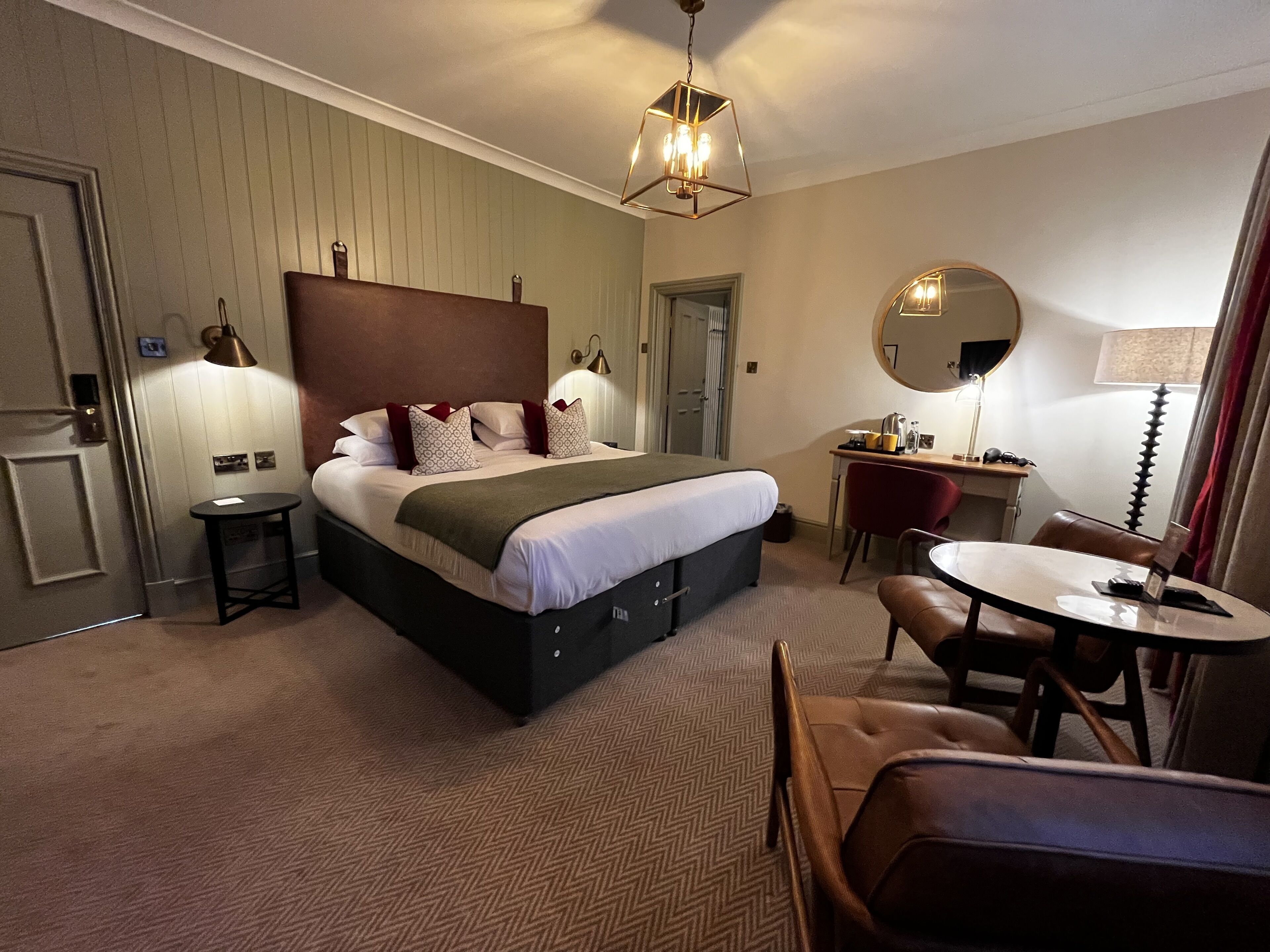 Ein Hotelzimmer mit einem großen Bett, einem Schreibtisch, einem Stuhl und einem runden Spiegel.