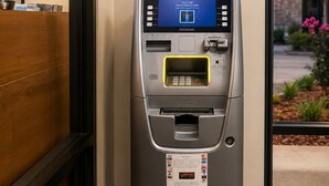 Un cajero automático con pantalla digital que muestra un mensaje de bienvenida, lector de tarjetas, dispensador de efectivo y ranura para recibos.