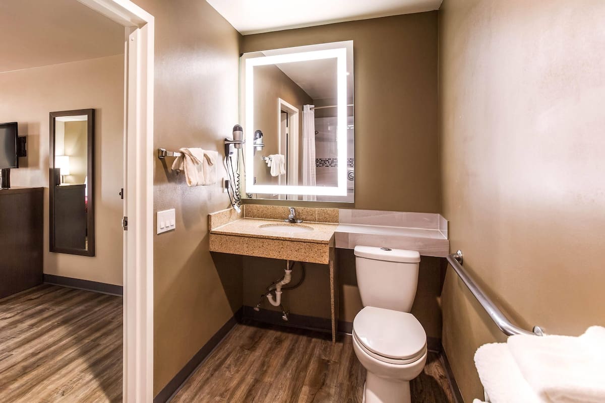 A compact bathroom with a sink, mirror, and toilet.