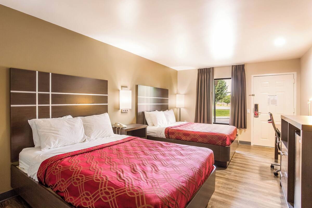 A hotel room with two beds, a desk, and a wardrobe.