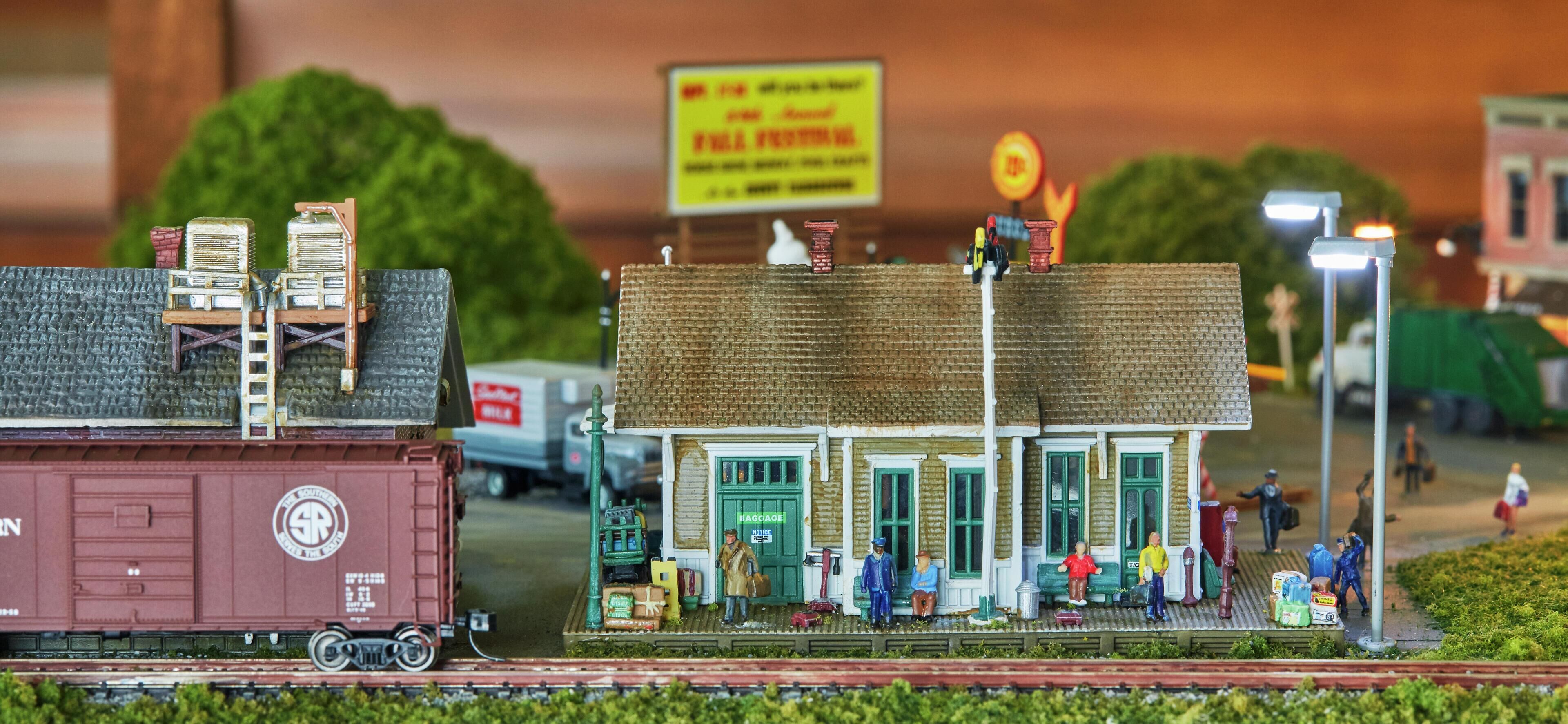 Un ensemble de trains miniatures comprenant une gare, des figurines et un conteneur de marchandises.