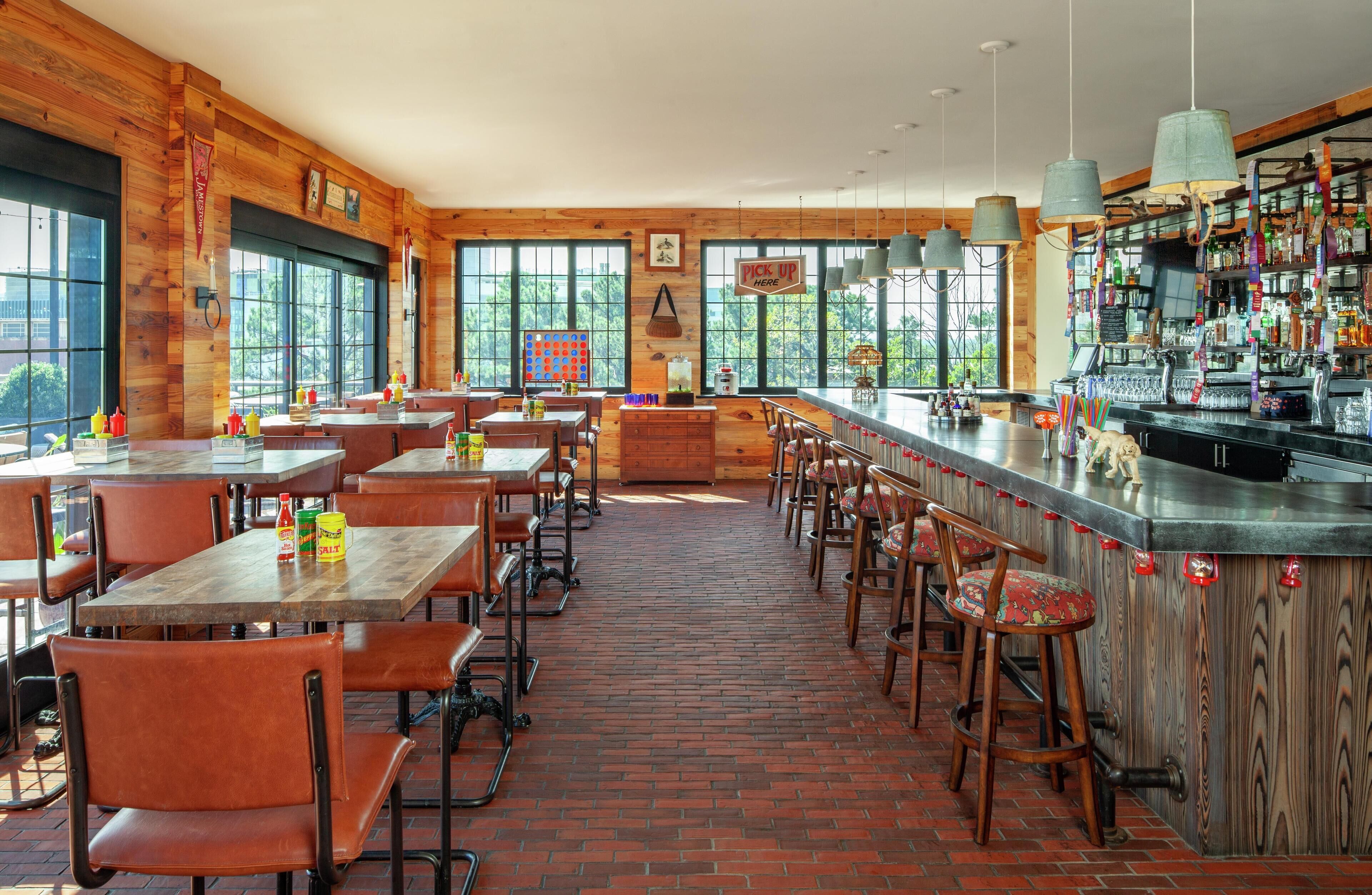 A restaurant with wooden interior, brick floor, and large windows.