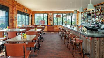 A restaurant with wooden interior, brick floor, and large windows.