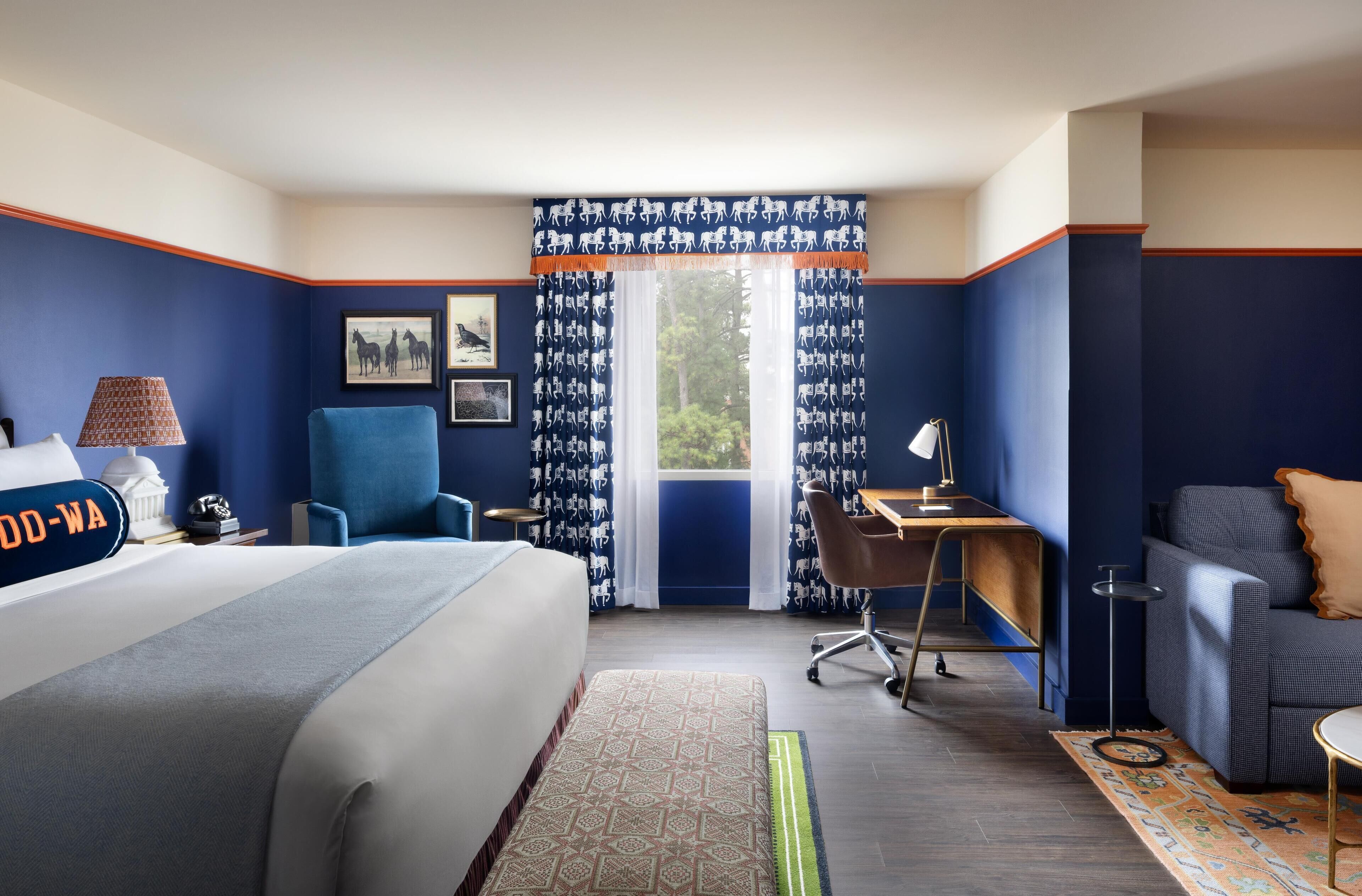 A hotel room with a bed, a desk, a chair, and a sofa.