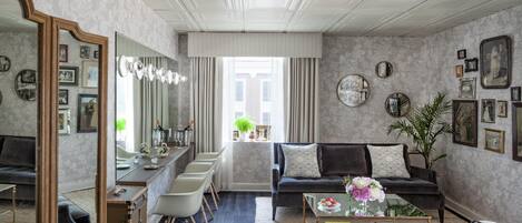 A spacious living room with a dark sofa, a coffee table with books, and a large mirror.