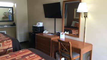 Une chambre d’hôtel équipée d’un lit, d’un bureau, d’une chaise, d’une télévision, d’un miroir et d’une lampe.