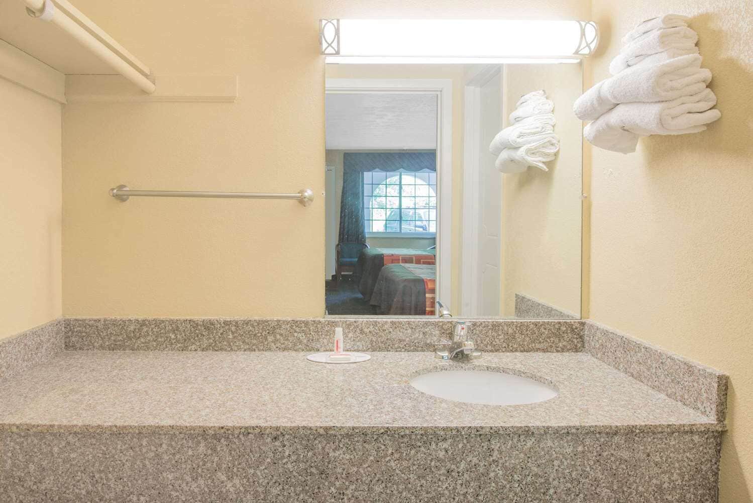A bathroom with a granite countertop, a sink, a mirror, and a towel rack.