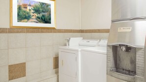 Un espace buanderie équipé d’un lave-linge et d’un sèche-linge, d’une fontaine à eau et d’un tableau encadré accroché au mur.