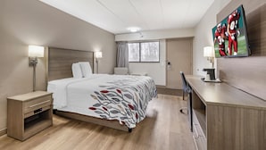 A hotel room with a bed, bedside tables, a desk, a TV, and a window. - Red Roof Inn Parsippany (Parsippany)
