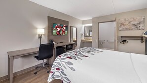 A hotel room with a bed, desk, chair, television, and a bathroom with a mirror and towel rack. - Red Roof Inn Parsippany (Parsippany)
