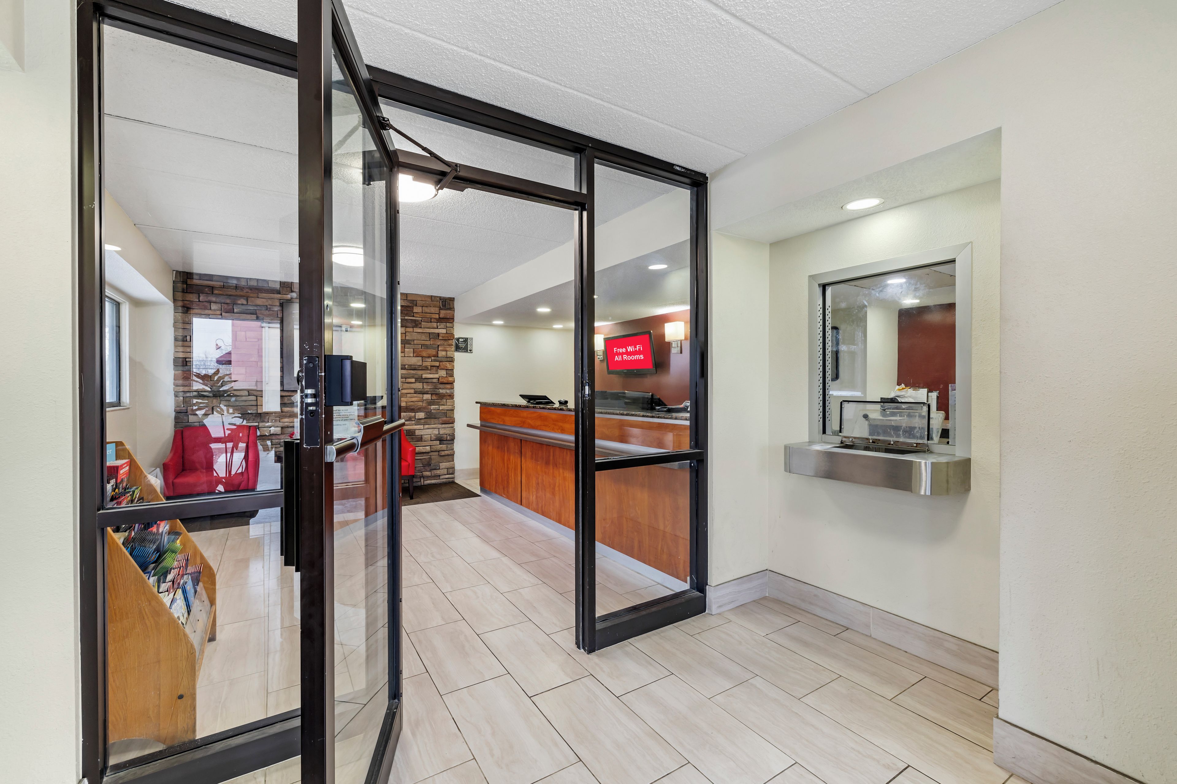 A hotel lobby with a reception desk, a stone accent wall, and a large mirror.