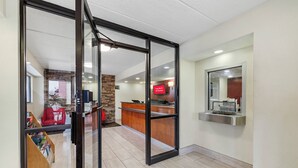A modern kitchen with a wooden countertop, a red chair, and a glass door leading to a living area. - Red Roof Inn Parsippany (Parsippany)