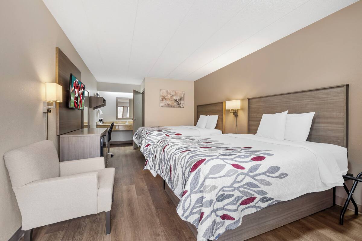 Ett hotellrum med en stor säng, en stol, ett skrivbord och ett litet pentry.