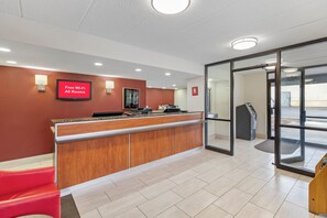 A reception area with a red wall, a digital screen advertising free Wi-Fi, a reception desk, and a glass door leading outside.