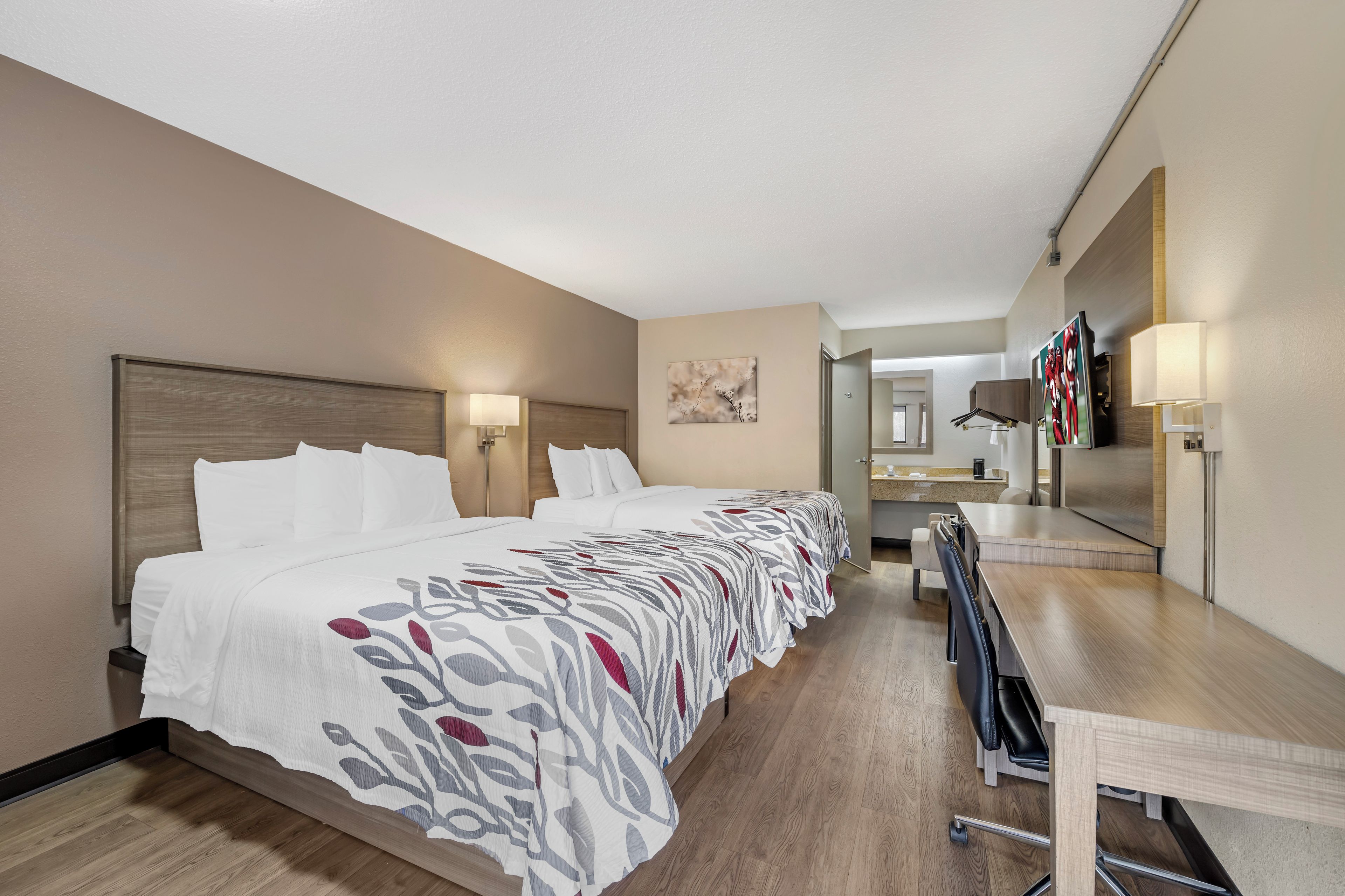 A hotel room with a large bed, a desk, and a mirror.