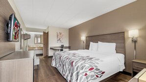Une chambre d’hôtel comprenant un lit, des tables de chevet, un bureau, une chaise, un téléviseur à écran plat et un tableau au mur.