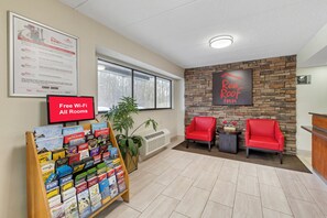 A Red Roof Inn reception area with a Red Roof Rewards program poster, a Red Roof Plus sign, a Red Roof mobile app download sign, a Red Roof Inn sign, a Red Roof logo, and a Red Roof Inn sign with a 4-star rating. - Red Roof Inn Parsippany (Parsippany)
