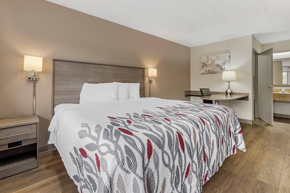 Ett hotellrum med en stor säng, sängbord, ett skrivbord och en stol.