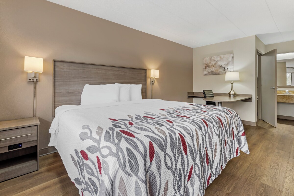 Une chambre d’hôtel comprenant un lit, des tables de chevet, un bureau, une chaise et une lampe.