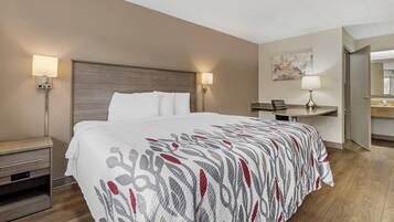 Une chambre d’hôtel comprenant un lit, des tables de chevet, un bureau, une chaise et une lampe.