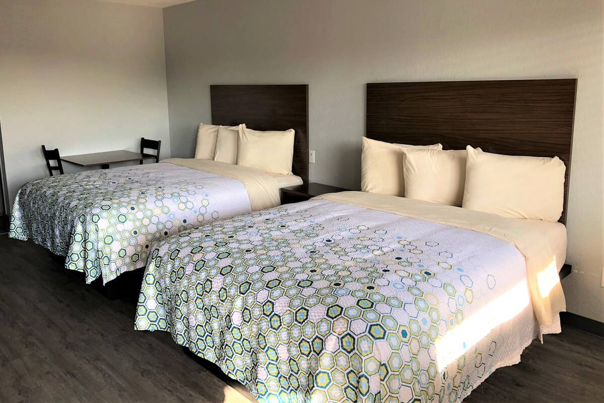 Ett hotellrum med två sängar, var och en med en sänggavel, ett litet bord och två stolar.