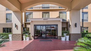 Entrada de hotel con un camino de ladrillo rojo, un acceso cubierto y un balcón superior.