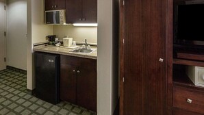 Una cocina compacta con microondas, cafetera y pileta.