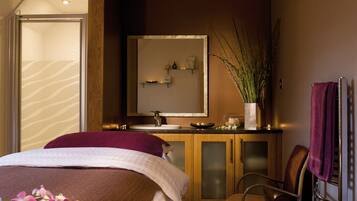 Habitación de hotel con una cama, una tocador de madera con espejo, una silla y un ventanal grande.