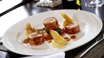 A white plate with sliced meat, vegetables, and sauce.