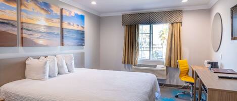 A hotel room with a large bed, a desk, a chair, and a window with curtains.
