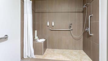 A walk-in shower with a grab bar, a towel rack, and a small sink.