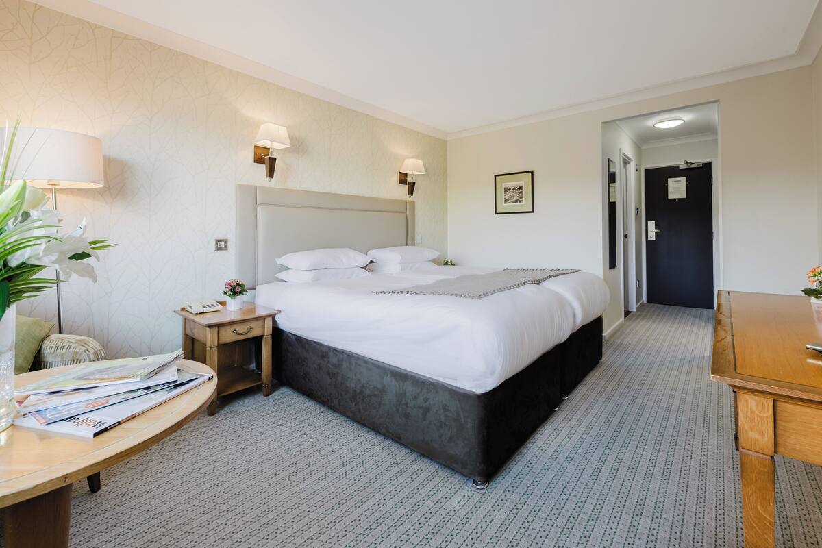 A hotel room with a large bed, bedside tables, a desk, and a chair.