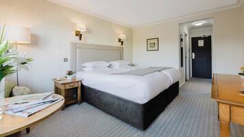 A hotel room with a large bed, bedside tables, a desk, and a chair.