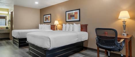 A hotel room with two beds, a desk with a chair, and a lamp.