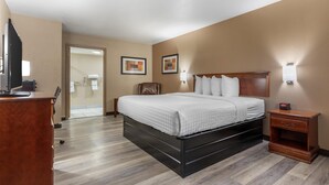 Una habitación de hotel con cama, mesita de noche, escritorio y silla.
