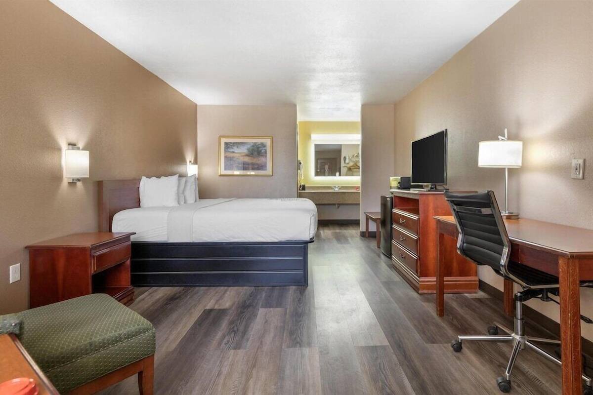 Ein Hotelzimmer mit Bett, Schreibtisch, Stuhl und Fernseher.
