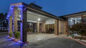 Un edificio moderno con fachada de ladrillo, amplios ventanales y una zona de acceso cubierta.