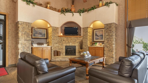 Una sala de estar acogedora con paredes de piedra, chimenea, sofás de cuero y televisor de pantalla plana.