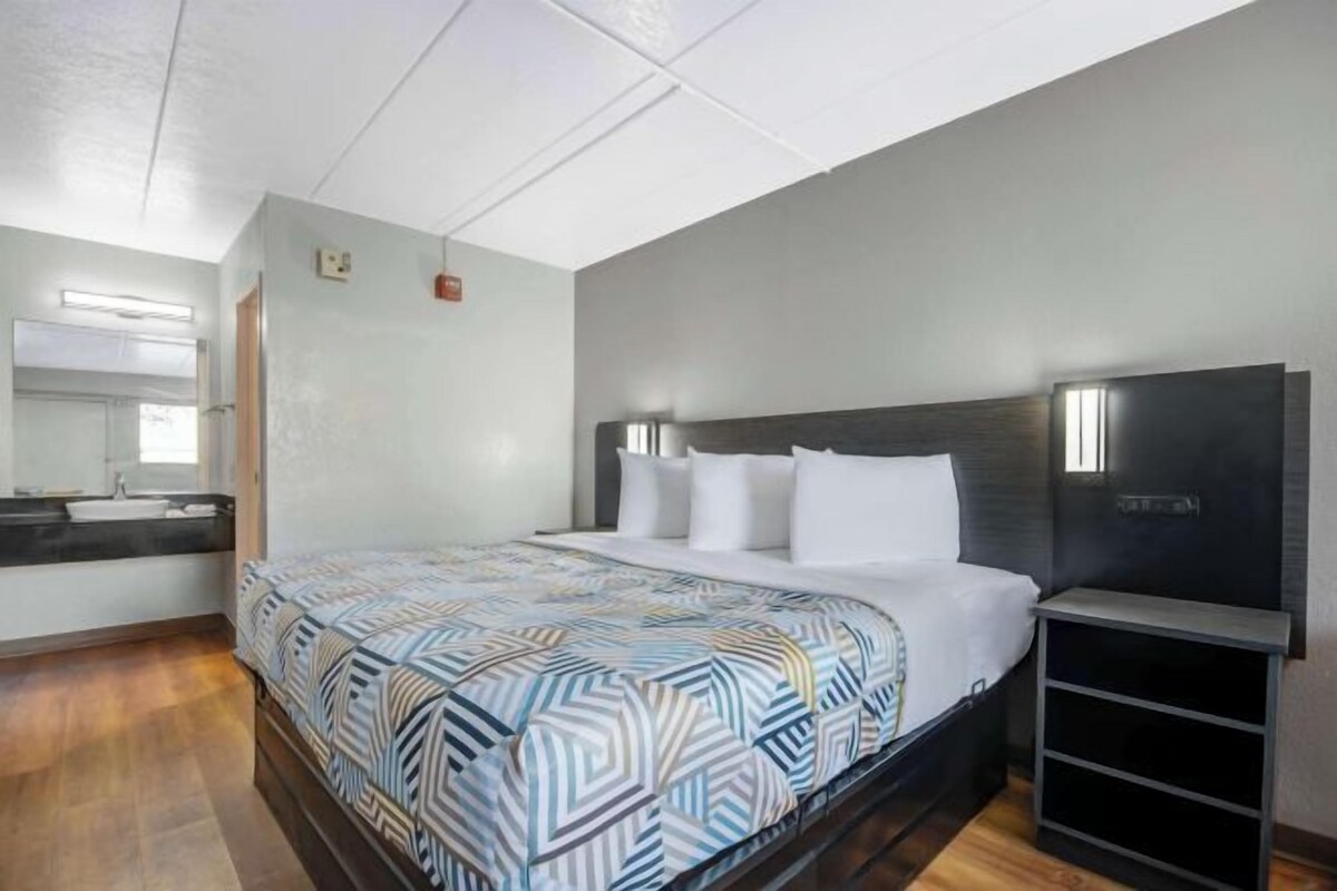 Een slaapkamer met een bed, nachtkastje, televisie en spiegel.